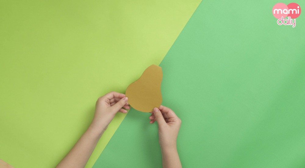 在淺啡色的畫紙上,畫上一個啤梨形狀,並剪下來備用