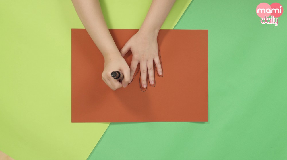 讓孩子把雙手放在深啡色畫紙上