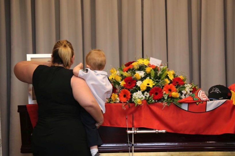 澳洲山火：哈維的母親抱住哈維，一同觀看父親的棺木和遺照