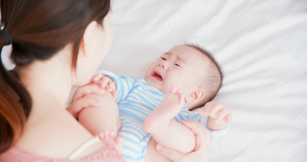 baby crying on bed.