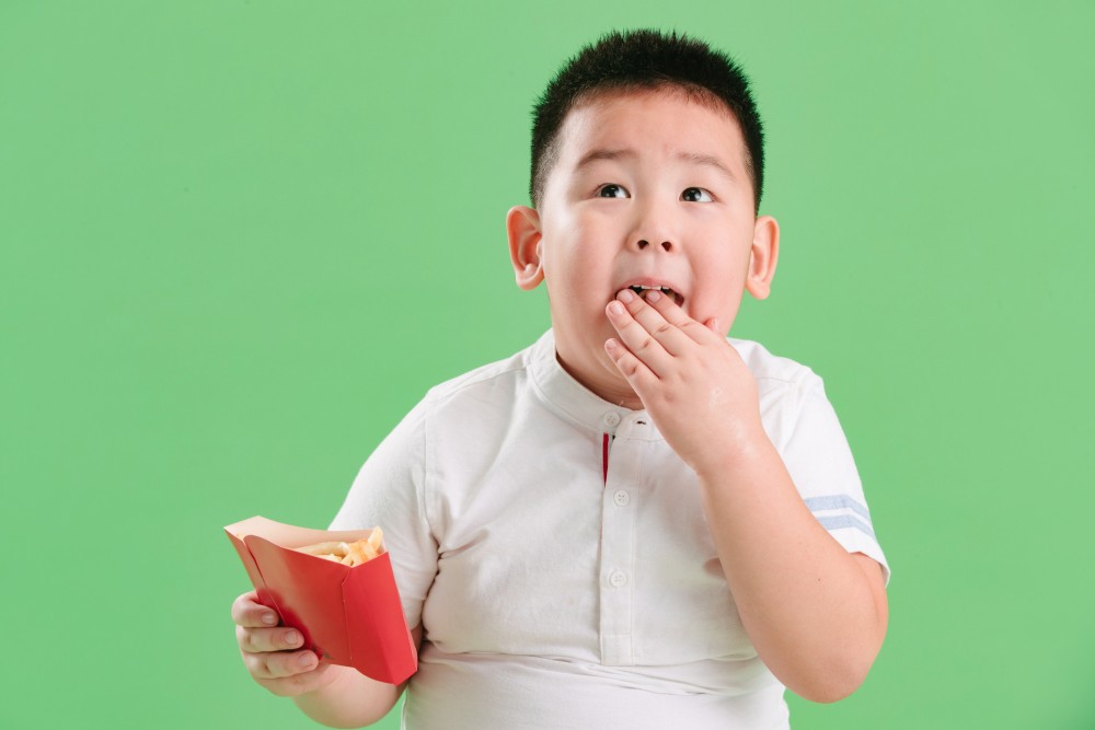 fat asian boy eating chips.