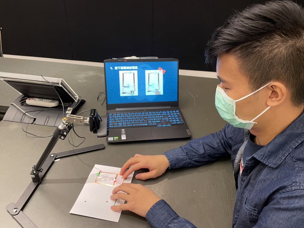 導師在網上教室中向學生示範使用銅貼紙及LED 燈泡製作閃閃發光的心意咭。