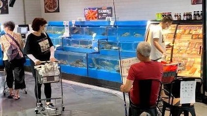 上海一家超市內竟有一名老人坐在魚缸垂釣,畫面可見他邊悠閒地看報紙邊釣魚。