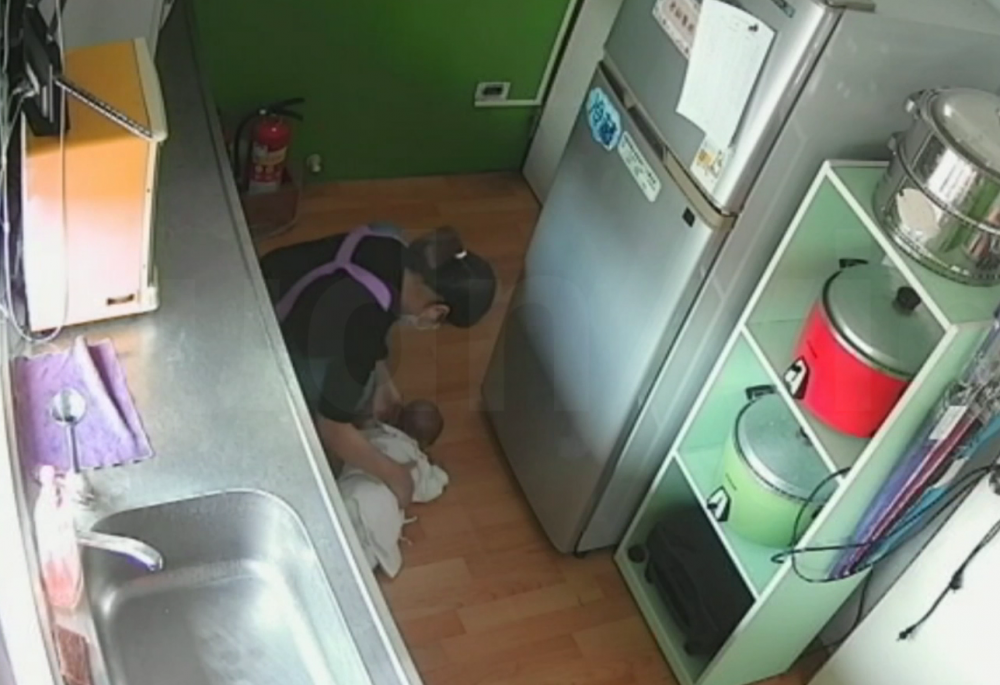 隨後職員再度進入,把布狀物塞進嬰兒嘴巴。