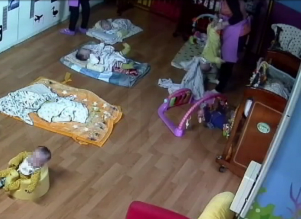 職員把嬰兒雙腳抓起,頭部倒掛