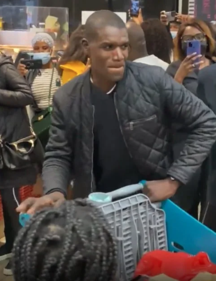 男子之後緩緩站起身，並默默地推着裝滿貨品的購物車跟在女方後面離開。