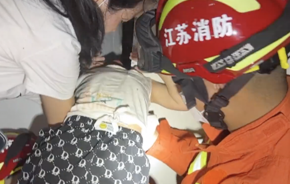 消防員慢慢托高女孩，方便打碎周邊牆壁。