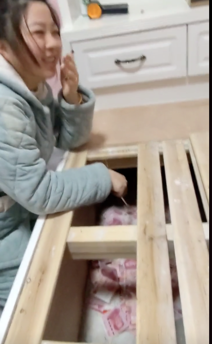 妻子拿著抓癢棒，邊笑邊勾出更多現金。