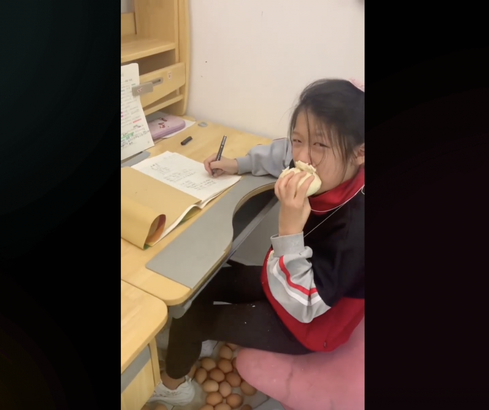 女兒一邊吃饅頭，一邊委屈做功課。